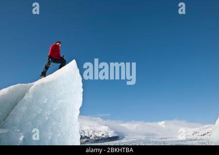 Femme grimpez l'iceberg sur le lagon du glacier de Fjallsjoull Banque D'Images