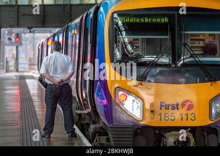 Premier chef de train Transennine Express attendant l'heure de départ à la gare de Leeds avec un signal rouge Banque D'Images