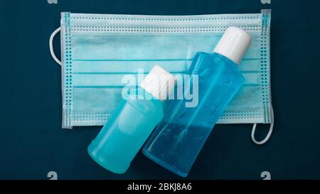 Masque hygiénique et gel d'alcool désinfectant pour les mains gel nettoyants pour les bactéries et virus sur fond bleu. Banque D'Images