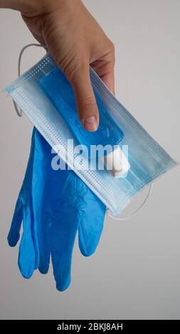 La main d'une femme tient des gants en caoutchouc pour l'hygiène des mains, une bouteille de désinfectant pour les mains et un masque chirurgical. Concept de médecine soins de santé. Banque D'Images