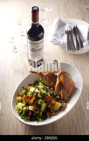 Confites de pommes de terre sautées de canard avec persil et bouteille de bon bordeaux Banque D'Images