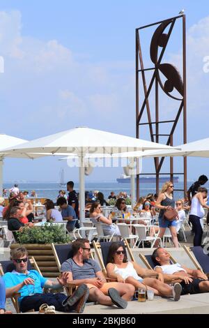 Portugal, Lisbonne, Ribeira das Naus, terrasse du café Quiosque Ribeira das Naus avec la sculpture sur les rives du Tage dédiée à l'artiste José Sobral de Almada Negreiros Banque D'Images