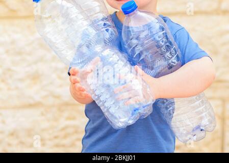 Petit enfant recyclant des bouteilles d'eau en plastique. Enfant qui sort les ordures séparées. Concept sans plastique, aucun déchet. Journée mondiale de l'environnement. Banque D'Images