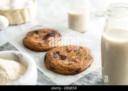 Délicieux biscuits aux pépites de chocolat sur un blanc avec des bouteilles de lait Banque D'Images