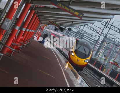 Virgin trains classe 390 Pendolino train 390009 passant la gare de Rugby sur la côte ouest ligne principale sous la pluie Banque D'Images