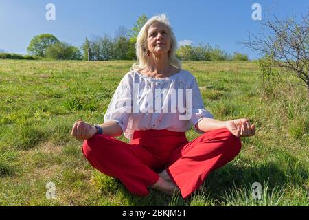 Europe, Luxembourg, Insenborn, femme âgée et attrayante méditant près du Lac Sûre Banque D'Images