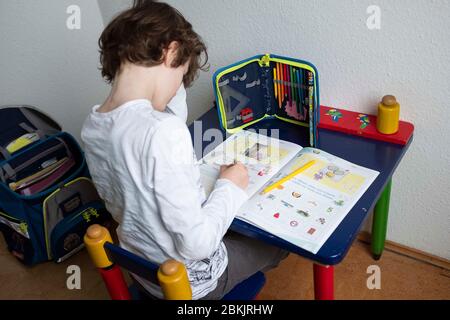 Erstklaessler (7 ans) est assis à une table à la maison et fait des tâches allemandes dans son livret "Alphabet livret - police de base", le 4 mai 2020 à Muelheim an der Ruhr/Allemagne. € | utilisation dans le monde entier Banque D'Images