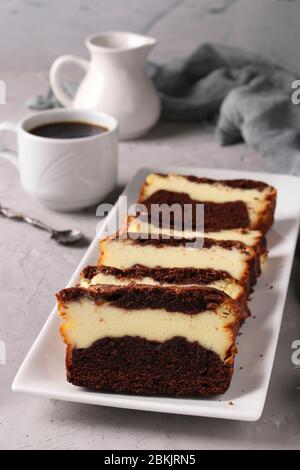 Muffin au chocolat fait maison en tranches avec fromage cottage situé sur une plaque blanche sur fond gris, format vertical Banque D'Images