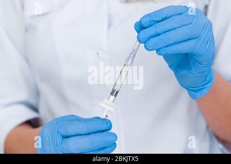 Gros plan d'une seringue avec une injection pour un lifting dans les mains d'un médecin. Cosmétologie d'injection. Banque D'Images
