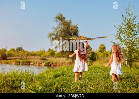 Joyeuses petites filles avec cerf-volant sur la prairie dans le parc de printemps. Enfants s'amusant à jouer à l'extérieur Banque D'Images
