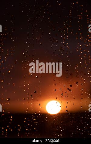 Un beau grand soleil doré au coucher du soleil aux pays-Bas. Gouttes de pluie sur une fenêtre en verre reflétant l'horizon ensoleillé. Création de couleurs orange douces Banque D'Images