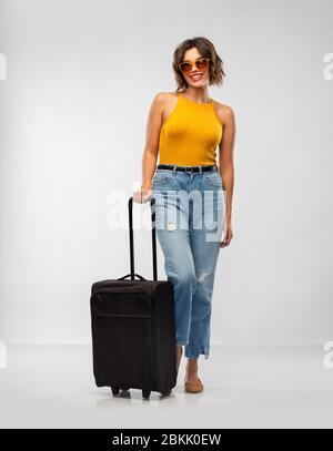 bonne jeune femme en lunettes de soleil avec sac de voyage Banque D'Images
