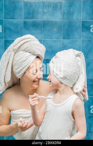 Une femme et un garçon avec des serviettes sur la tête se brossant les dents. Banque D'Images