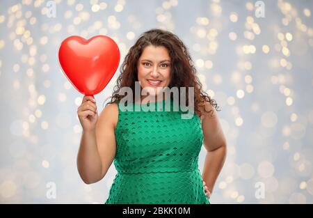 Happy woman holding red heart shaped balloon Banque D'Images