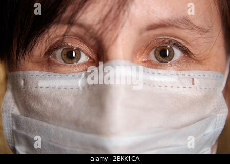 Les yeux bruns d'une femme d'âge moyen sur un masque facial protecteur lors d'une pandémie Covid-19 ou d'une infection à coronavirus. Banque D'Images