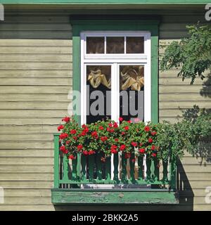 Ancien balcon en bois vintage avec fleurs rouges en pleine floraison le jour d'été Banque D'Images