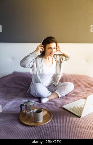 Jeune femme heureuse grise se détendant à la maison, appréciant le temps pour elle-même avec le café. Loisirs avec appareil technologique, couleurs pastel, espace de copie Banque D'Images