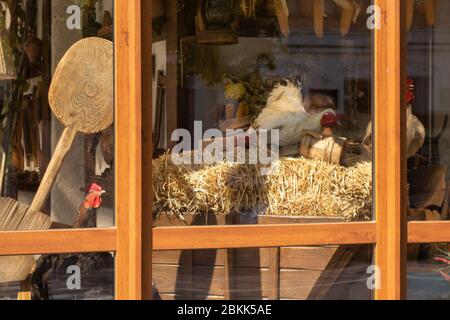 Poules et coq sur un foin dans un chariot à l'extérieur de la fenêtre d'une maison de village. Banque D'Images