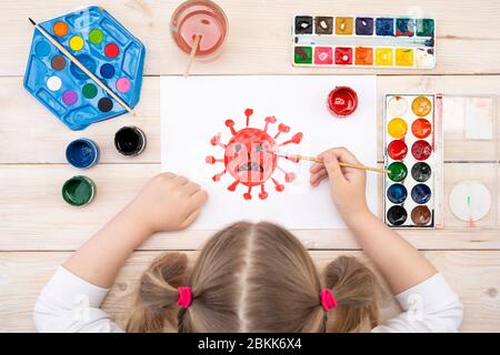 Un enfant dessine un coronovirus sur un morceau de papier. Le dessin a été réalisé par un enfant en utilisant des peintures de couleur. Dessin des enfants. Vue de dessus Banque D'Images