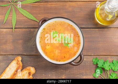 Soupe de légumes infusée au cannabis dans un bol sur une table en bois, vue du dessus avec espace pour le texte Banque D'Images