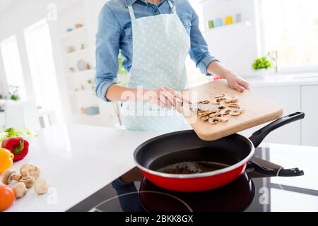 Photo de la femme au foyer chef tenir le champaignon coupe des tranches de couteau mettre sur la poêle cuisson savoureux dîner famille réunion porter tablier chemise stand Banque D'Images