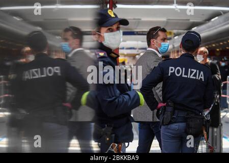 Les policiers vérifient les passagers portant des masques de protection après leur arrivée à la gare centrale de Naples, dans le sud de l'Italie, avec un train à grande vitesse Frecciarossa. Les passagers se sont clairement encorés et ont suivi le chemin indiqué par la police, s'alignant pour faire contrôler la température de leur corps sur la plate-forme du poste. Le gouvernement italien lève progressivement les restrictions de verrouillage qui ont été mises en œuvre pour endiguer la propagation du coronavirus à l'origine de la maladie de Covid-19. Banque D'Images