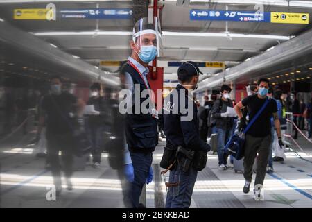 Les policiers vérifient les passagers portant des masques de protection après leur arrivée à la gare centrale de Naples, dans le sud de l'Italie, avec un train à grande vitesse Frecciarossa. Les passagers se sont clairement encorés et ont suivi le chemin indiqué par la police, s'alignant pour faire contrôler la température de leur corps sur la plate-forme du poste. Le gouvernement italien lève progressivement les restrictions de verrouillage qui ont été mises en œuvre pour endiguer la propagation du coronavirus à l'origine de la maladie de Covid-19. Banque D'Images