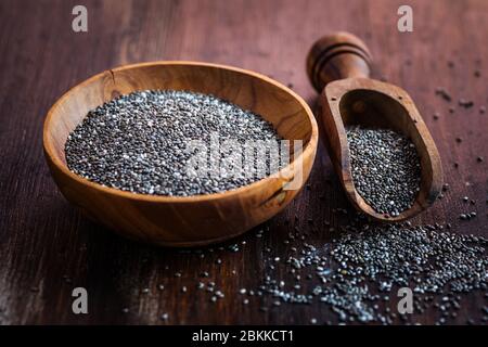 Graines de Chia nutritives avec une cuillère dans le bol sur fond de bois Banque D'Images