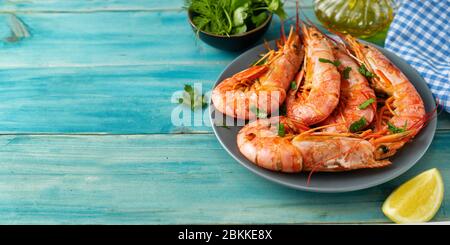 Grosses crevettes rouges dans une assiette sur fond bleu clair Banque D'Images