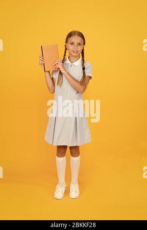 Journal intime pour les filles concept. happy little girl en rétro vintage kid fashion. uniforme. retour à l'école. girl cahier hold ou notepad. livre encyclopédie pour les enfants. petite fille l'amour de la littérature. La vieille école. Banque D'Images