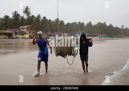 Sur la côte de Goa en Inde, deux hommes portent des cordes pour les bateaux de pêche. Banque D'Images