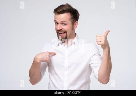 Un homme à barbe heureux se montre avec des pouces, sourires heureux, pointant vers le torse en se vantant. Je suis génial. Prise de vue en studio Banque D'Images