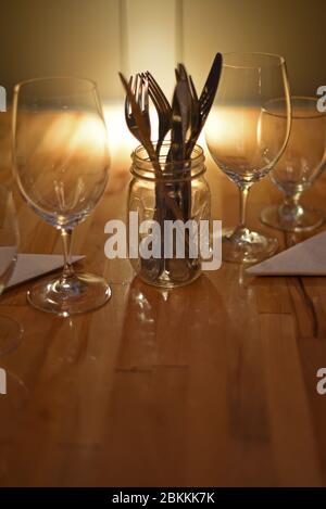 Les couverts sont assis dans un pot en verre à côté des verres à vin et à eau, qui fait partie d'un cadre de table pour un repas Banque D'Images