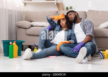 Nettoyage du ressort d'évacuation. Un couple africain fatigué se reposant sur le sol après avoir lassé à plat Banque D'Images