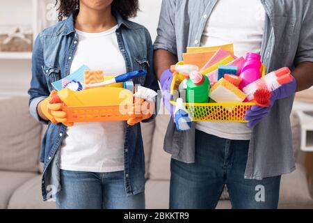 Seaux avec produits de nettoyage dans les mains d'un couple noir méconnaissable Banque D'Images