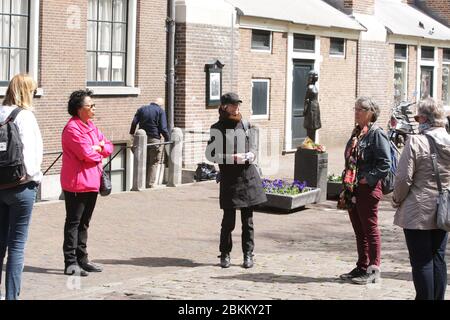 Les habitants de la région s'y rendent à distance sociale près des fleurs posées à la statue d'Anne Frank (1929-1945) près de la maison d'Anne Frank sur une rue vide pendant la Banque D'Images