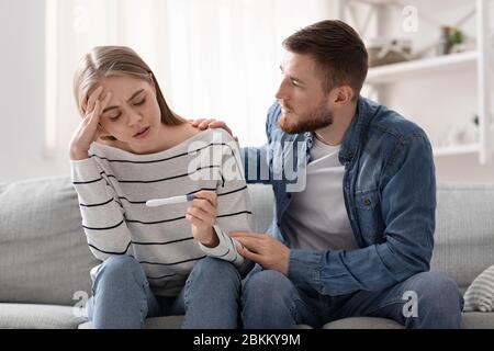 Homme et femme bouleversés regardant le test de grossesse négatif Banque D'Images