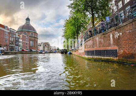 Au niveau de l'eau vue depuis le canal Singel à Amsterdam, Pays-Bas avec l'église luthérienne ou Ronde Ronde Lutherse Kerk à voir sur une journée d'automne nuageux Banque D'Images