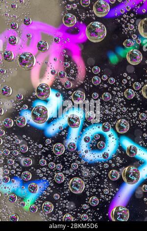 Inscription « WORD LOVE » à travers des gouttes d'eau sur verre, vue macro Banque D'Images