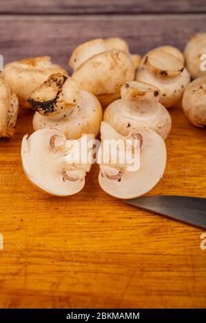 Moitiés de champignons coupés et de jeunes champignons dispersés sur fond de bois. Gros plan Banque D'Images