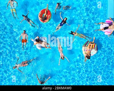 Antenne d'amis ayant une fête dans la piscine avec flamants gonflables, cygne, matelas. Les jeunes se détendre dans un complexe de luxe le jour ensoleillé. Afficher Banque D'Images