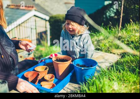 Une mère et son enfant d'âge préscolaire plantent des graines dans des pots à l'extérieur le printemps Banque D'Images