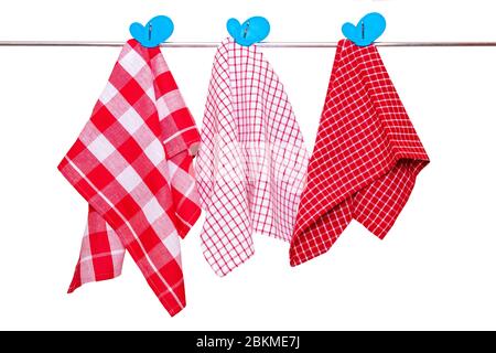 Serviettes de bain isolées. Gros plan de diverses serviettes de cuisine à damier rouge avec des clous de girofles bleus pendent sur un rail de vêtements isolé sur un fond blanc. Banque D'Images