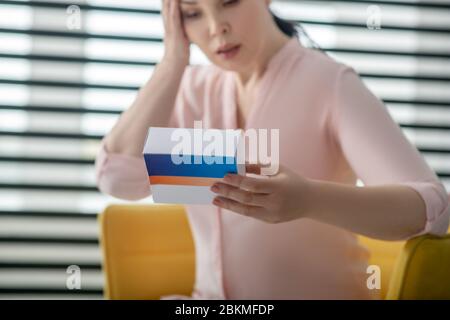 Femme dans la blouse rose avec boîte de pilules dans sa main. Banque D'Images