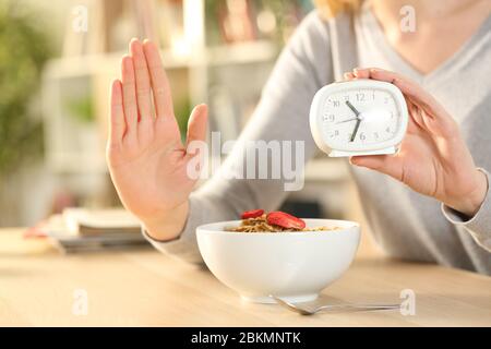 Gros plan des mains de femme sur le jeûne intermittent faisant signe d'arrêt attendant avant de manger un bol de céréales sur une table à la maison Banque D'Images