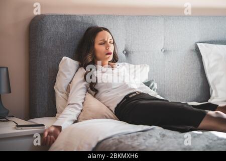 Une femme d'affaires fatiguée est couchée sur le lit de l'hôtel. Banque D'Images