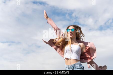 La jeune fille caucasienne aime écouter de la musique sautant pour la joie dans un parc de la ville. Banque D'Images