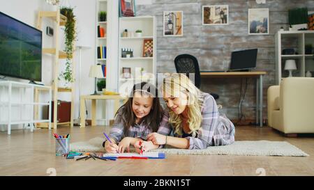 Belle jeune mère enseignant à sa petite fille de dessiner. Banque D'Images