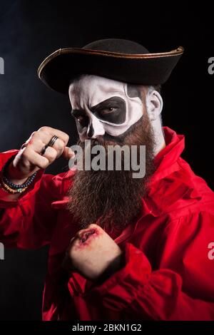 Homme barbu médiéval avec costume de pirate pour halloween sur fond noir. Banque D'Images