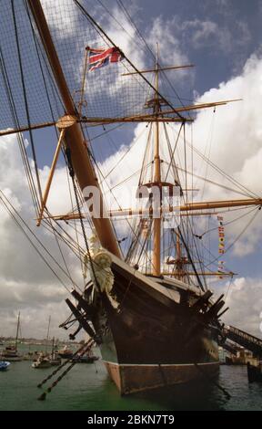 H.S. Guerrier dans le chantier naval de Portsmouth, Hampshire, Angleterre, vu de fin sur l'arc de port, grand angle. Soleil et cumulus Banque D'Images